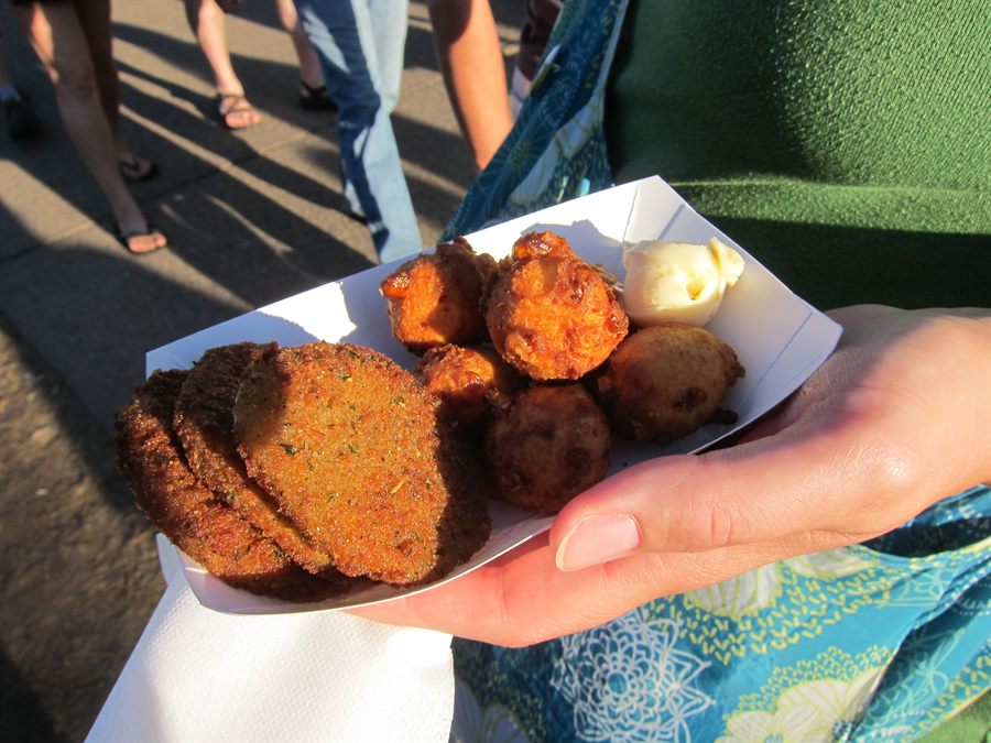 Golden-hour tray of darkly seasoned fried green tomatoes and fritters with butter