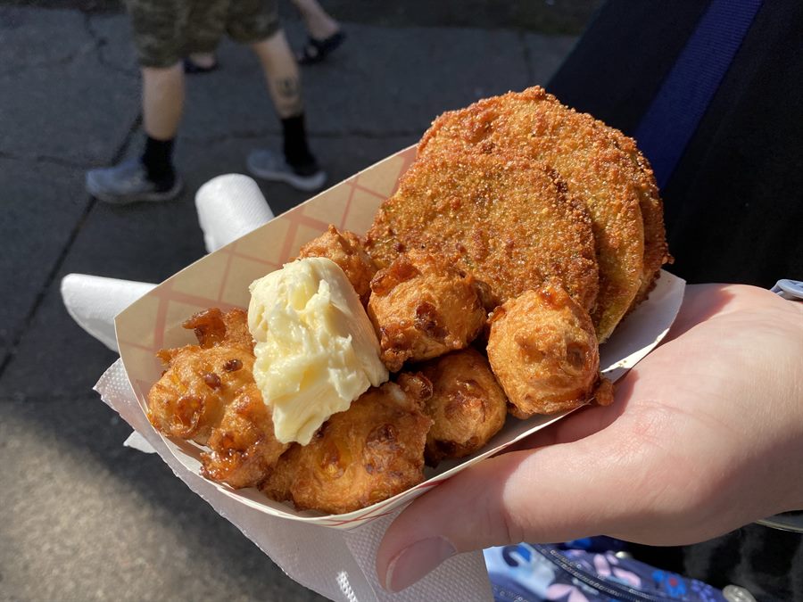 Close-up of a tray of corn fritters with a large scoop of honey butter and fried green tomatoes
