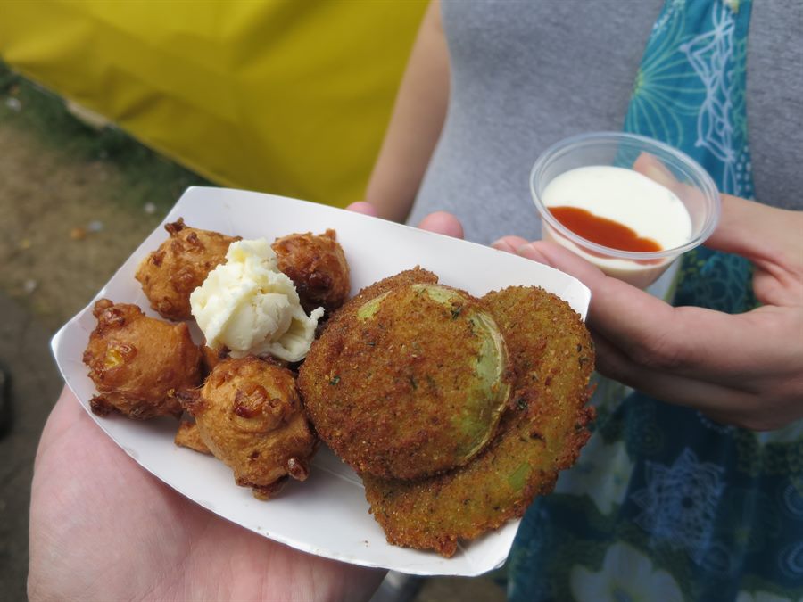 Tray of fritters and fried green tomatoes with a cup of ranch striped with hot sauce